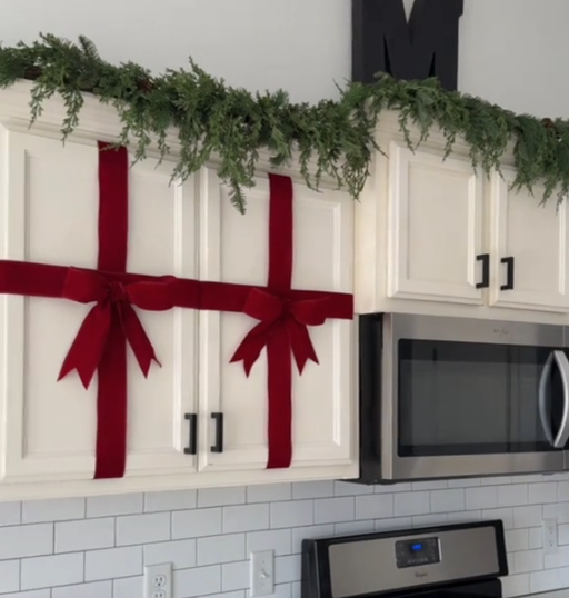Burgundy cabinet bows with greenery in a white kitchen
